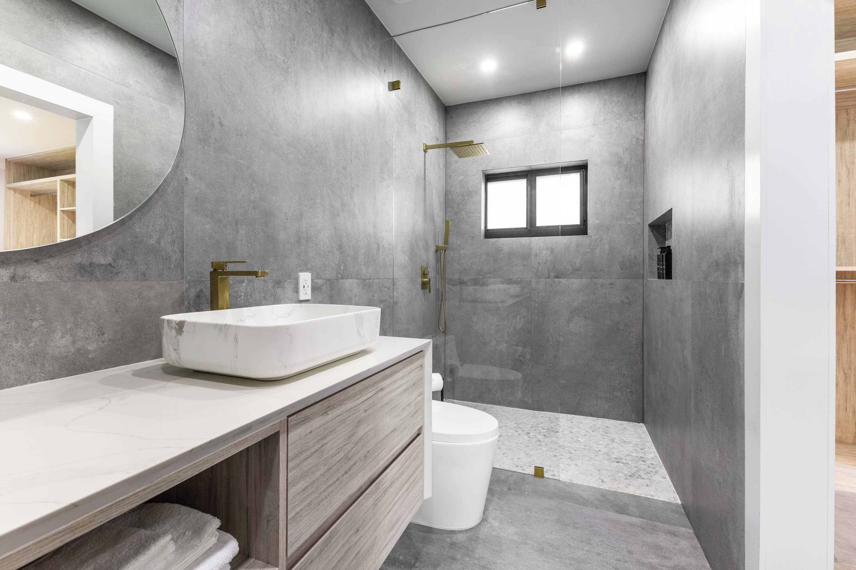 A modern bathroom with a large sink, vanity, and shower area.