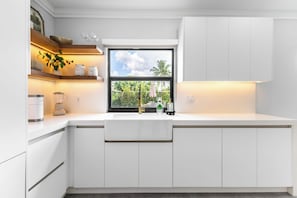 A modern kitchen with white cabinetry, a built-in window, and a countertop with a blender and jars. - Homestead Keys Gateway - Private Pool & Gym (Homestead)