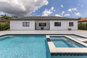 A two-story house with a swimming pool in front.