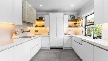 A modern kitchen with white cabinetry, a built-in oven, and a window providing a view of greenery outside.