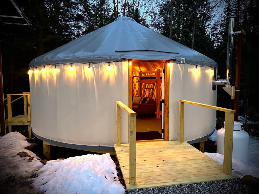 A yurt with a wooden entrance and a platform.