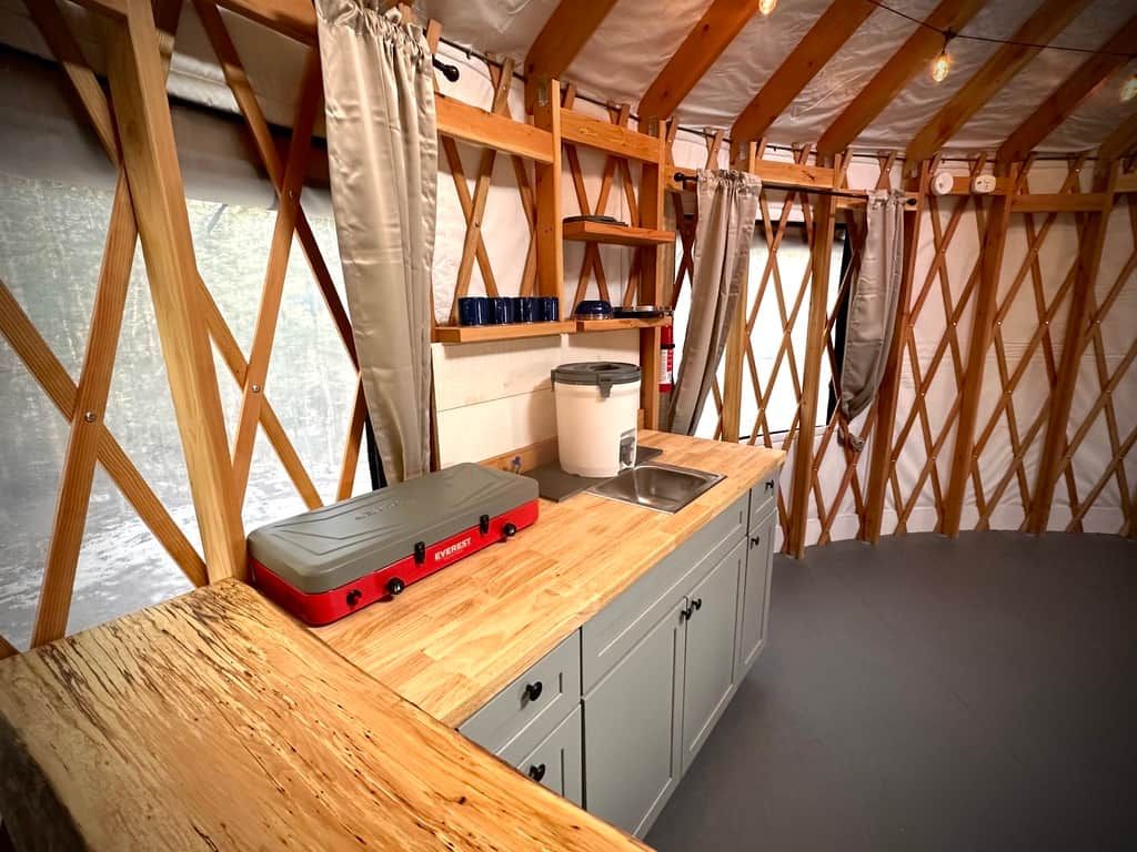 A compact kitchen with a wooden countertop, a sink, and a storage unit.