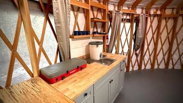 A compact kitchen with a wooden countertop, a sink, and a storage unit.