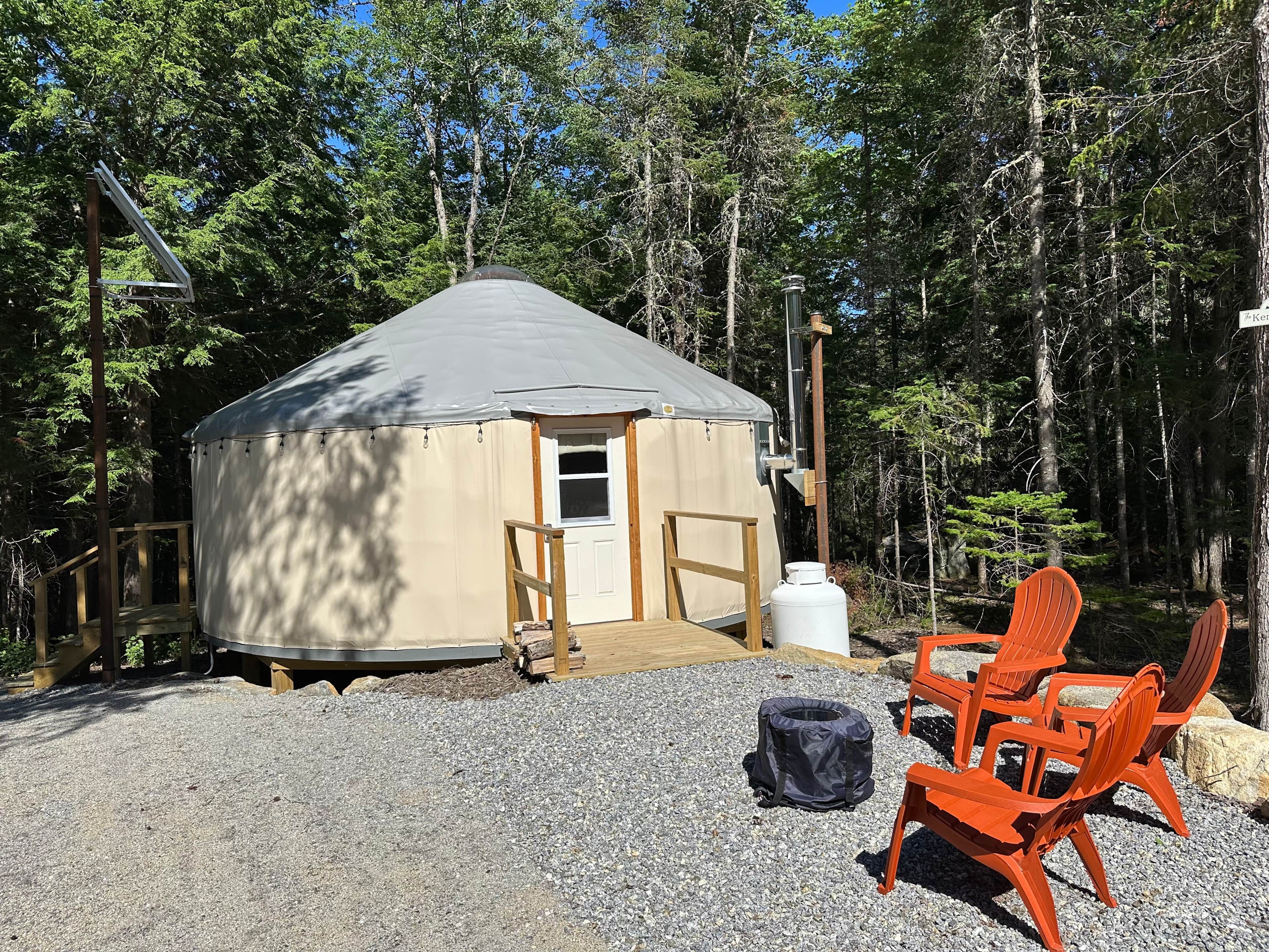 A yurt with a door, a small porch, and a gravel ground.