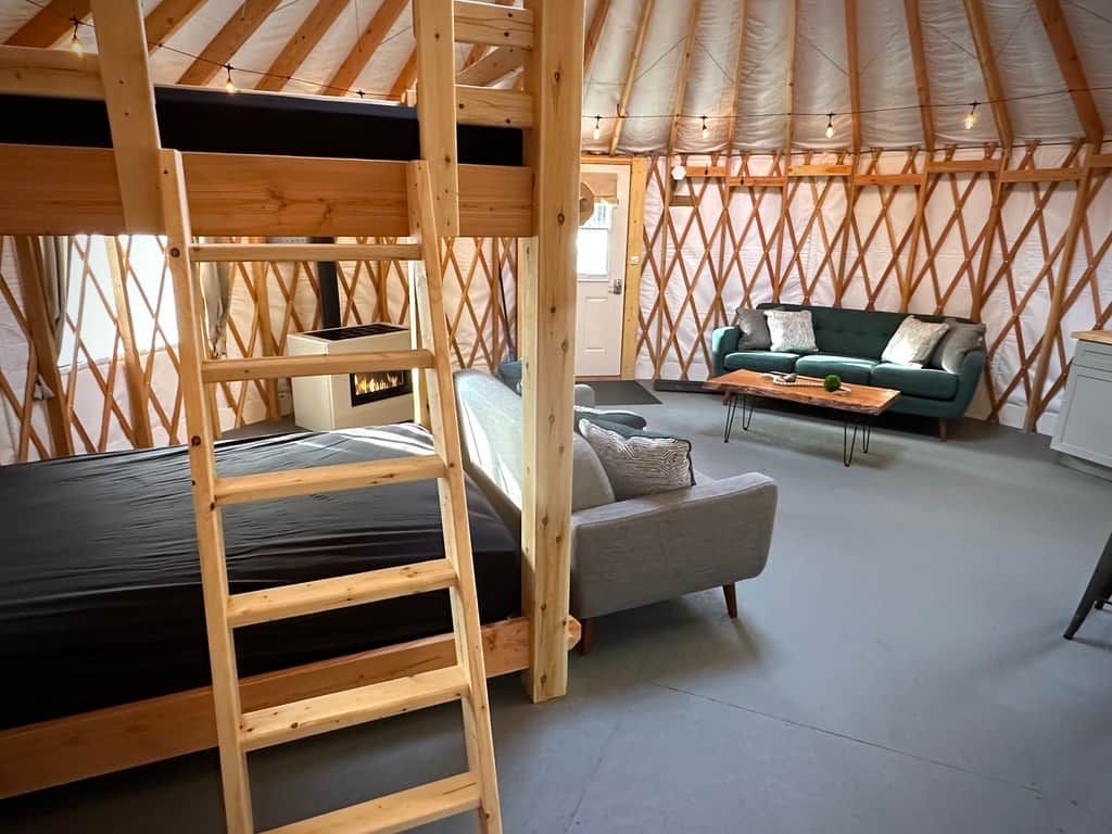 En ombonad interiör i en träbyggnad med en våningssäng, en soffa och ett matbord.