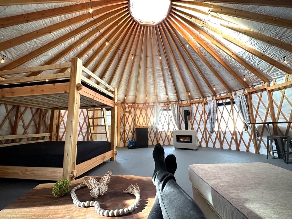 A cozy interior with a circular wooden ceiling, a bed, a sofa, and a small table.