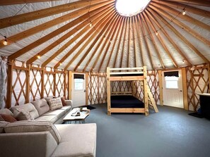 En yurts indretning med trævægge, køjeseng, sofa og et lille bord.