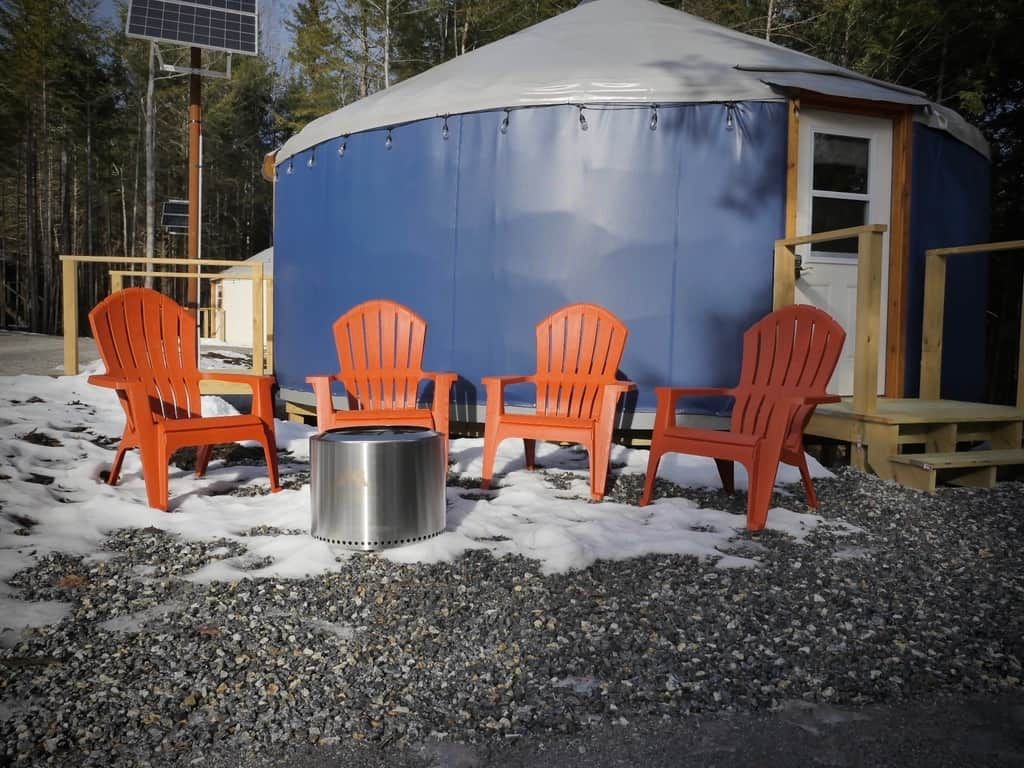 A blue tent with orange chairs and a metal container, surrounded by gravel and snow.