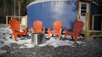A blue tent with orange chairs and a metal container, surrounded by gravel and snow.