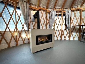 A room with a fireplace, wooden lattice walls, and a window with curtains.