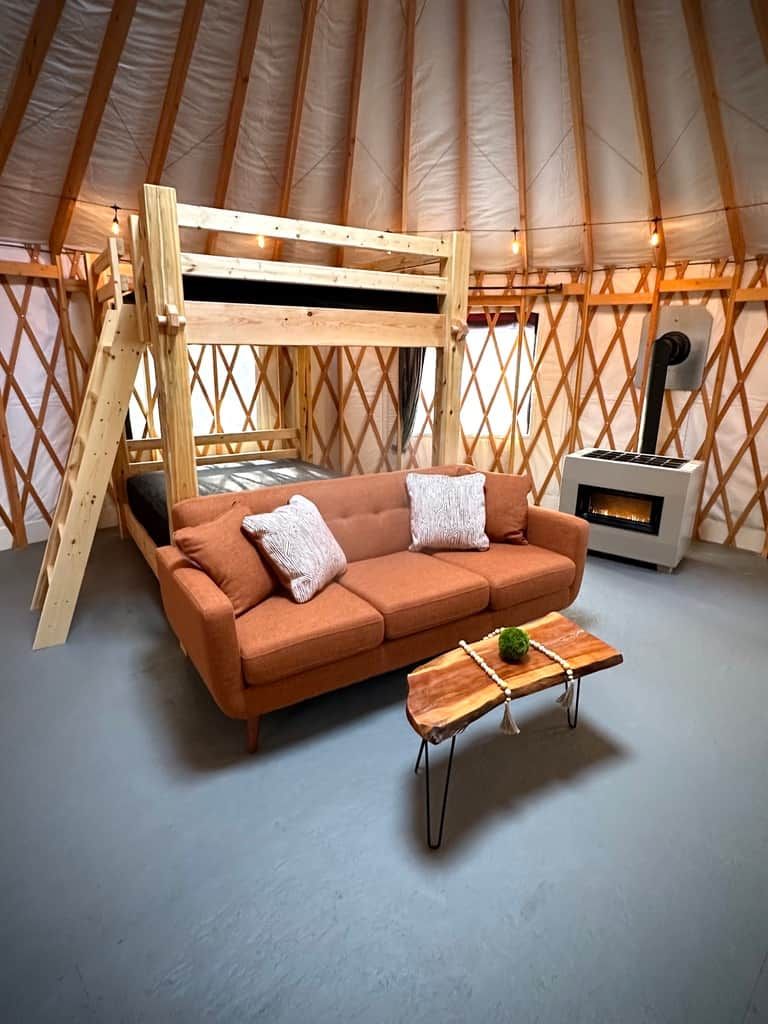 Een gezellig interieur van een joert met een bank, een klein tafeltje en een open haard.