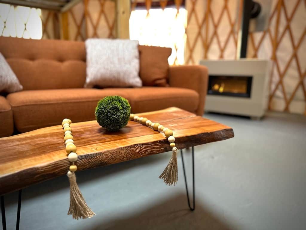 Een houten bijzettafeltje met een decoratieve kralenketting en een groene, bolvormige object.