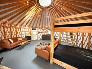 A yurt interior with a bunk bed, sofa, and a small dining area.