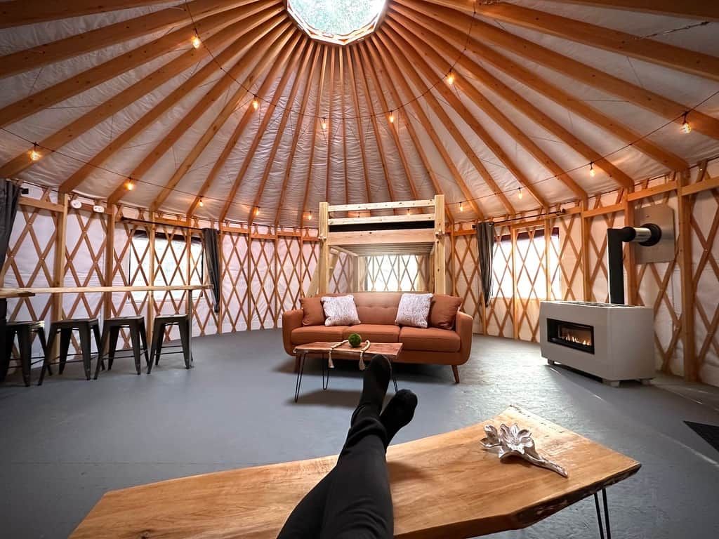 A yurt interior with a sofa, table, and a fire pit.