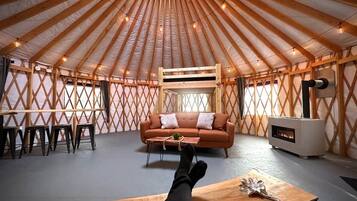 A yurt interior with a sofa, table, and a fire pit.