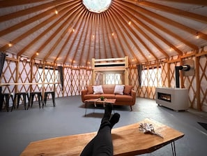 A yurt interior with a sofa, table, and a fire pit.