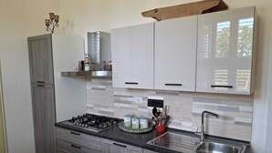 Cozinha compacta com fogão a gás, pia e armários.