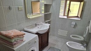 Casa de banho compacta com máquina de lavar, lavatório e sanita.