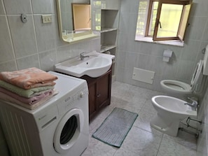 Pieni kylpyhuone, jossa on pesukone, pesuallas ja wc.