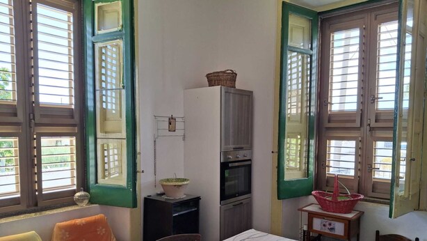 Quarto com cama, mesa, armário e janela com persianas.