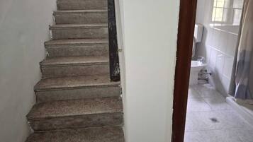 Un escalier avec une rampe noire menant à un sol carrelé.