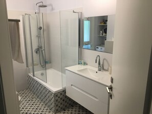 Ein modernes Badezimmer mit einer Duschkabine, einer weißen Badewanne und einem Waschtisch mit Spiegel.