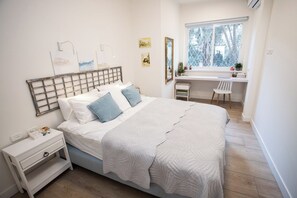 Ein Schlafzimmer mit einem Bett, einem Nachttisch und einem Schreibtisch mit Stuhl.