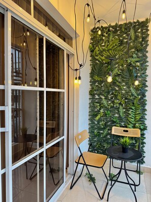 A room with a large window, a wall-mounted plant wall, and a small table with chairs.