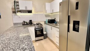 A kitchen with white cabinets, a stainless steel refrigerator, a gas stove, and a microwave. - 3-Bedroom Apartment 20 Minutes from AILA and the Colonial District (Santo Domingo Este)