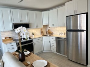 A modern kitchen with white cabinets, stainless steel appliances, and a wooden countertop. - One Bedroom Condo with amazing Bayviews #504 (Fort Myers Beach)