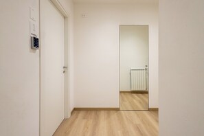 A hallway with a door, a wall-mounted security keypad, and a large mirror reflecting a radiator. - CordiAle Suites Pisa (Pisa)