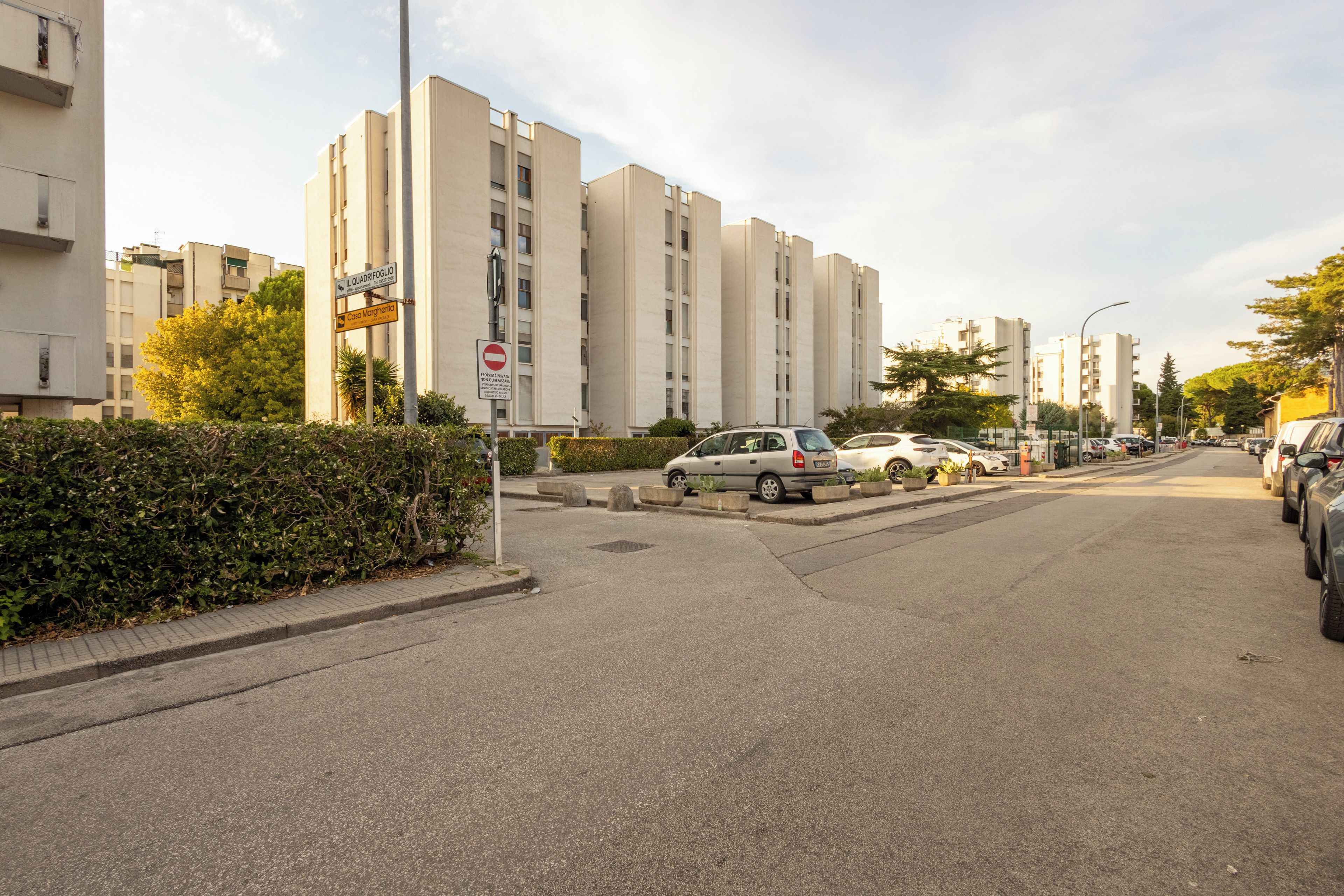 A street with parked cars, a no entry sign, and residential buildings.