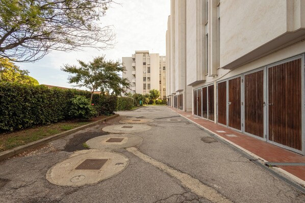 Una calle residencial con edificios de apartamentos, aceras y una fila de setos.