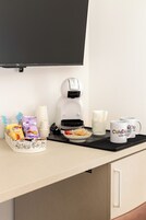 La colazione in camera: una macchina per caffè, un piatto di pasticcini, un vassoio con salse e una tazza con decorazioni a cuore.