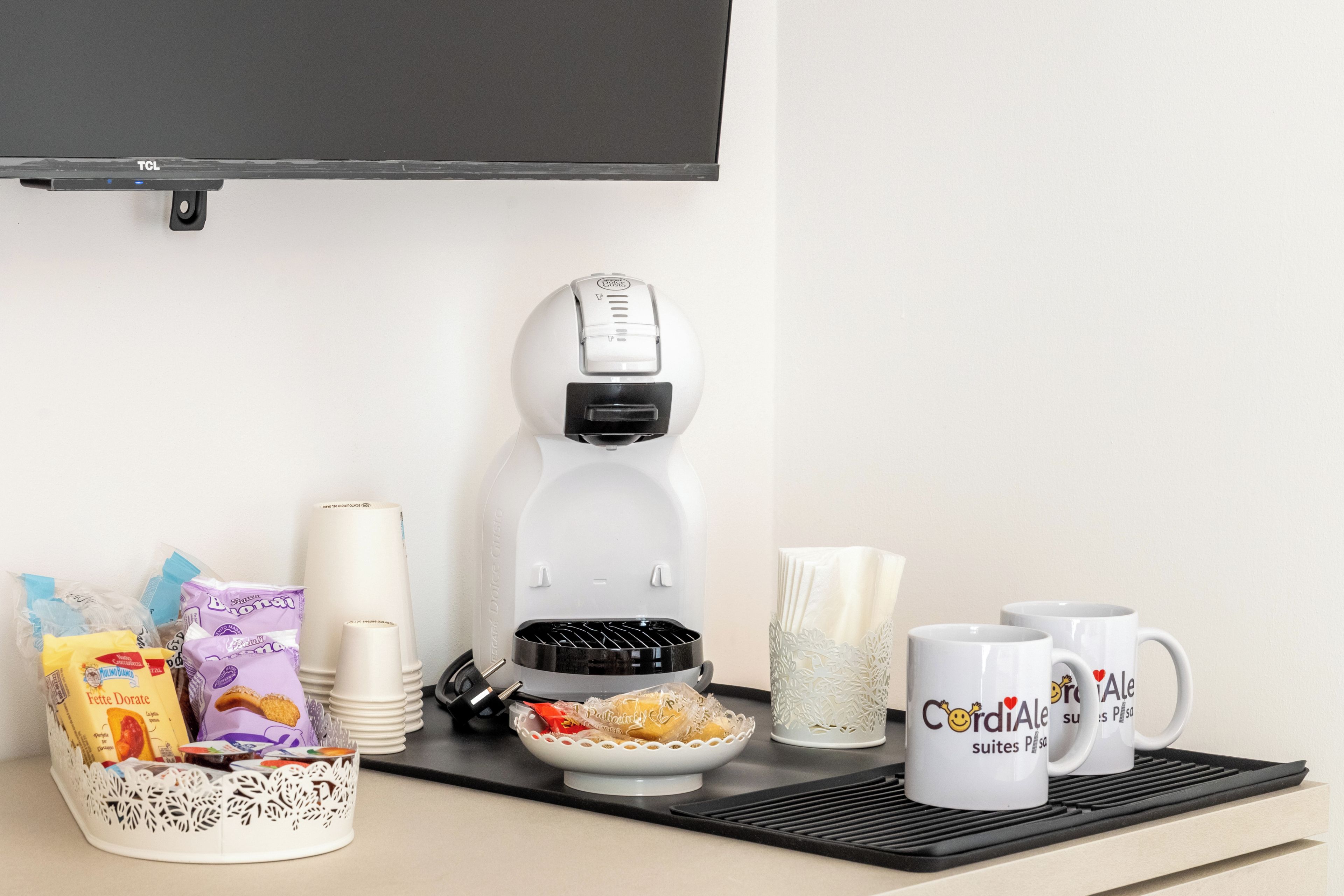 A breakfast setup with a coffee machine, a bowl of cereal, and a mug with a heart design.