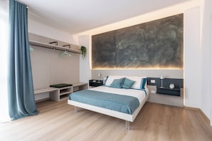 A modern bedroom with a bed, bedside tables, a wall-mounted abstract art piece, and a hanging plant. - CordiAle Suites Pisa (Pisa)