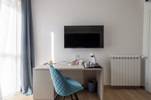 Una habitación moderna y minimalista con escritorio, televisor de pantalla plana, cafetera y radiador.
