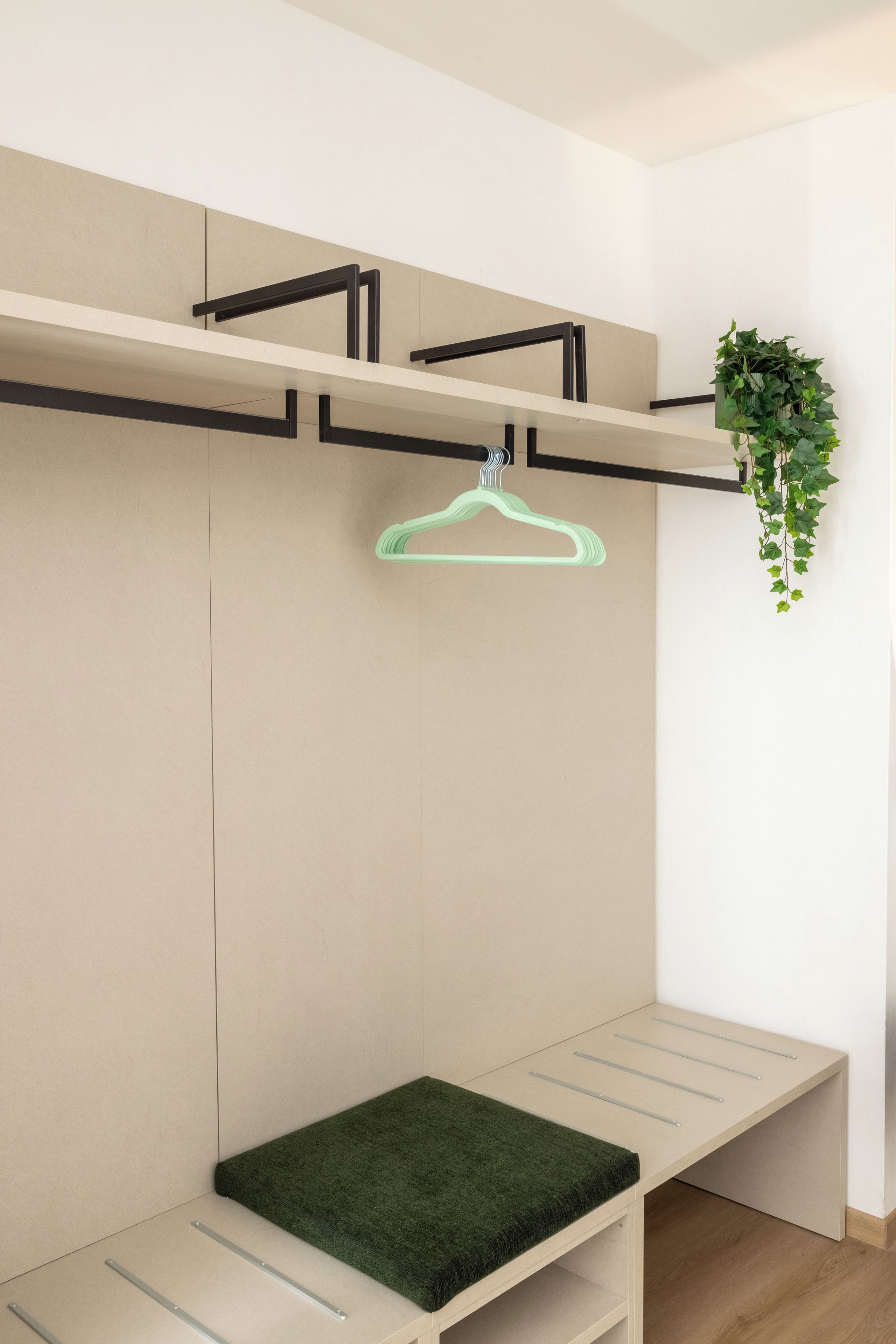 Een minimalistisch ingerichte kamer met een bankje, een hangende groene plantenhouder en een potplant.