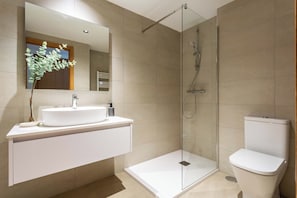 Ein modernes Badezimmer mit einer gläsernen Duschkabine, einem weißen Waschbecken und einer Toilette.