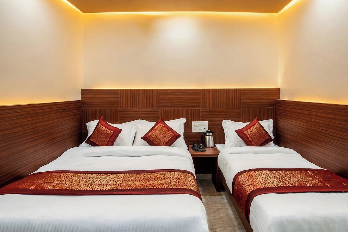 Une chambre d’hôtel avec deux lits, une table de chevet avec un téléphone et une machine à café, et une tête de lit en bois.