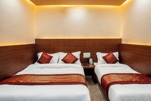 A hotel room with two beds, a nightstand with a phone and a coffee maker, and a wooden headboard. - Hotel Shiv Anand House New Delhi  (New Delhi)