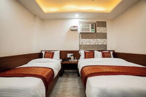 A hotel room with two beds, a nightstand with a phone and a coffee pot, and an air conditioning unit on the wall. - Hotel Shiv Anand House New Delhi  (New Delhi)