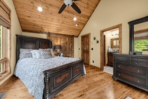 Une chambre à coucher avec un grand lit, un plafond en bois et une commode.