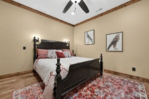 A bedroom with a bed, wooden floor, ceiling fan, and two wall-mounted bird paintings. - Mountain-View Home w/ 3 Fireplaces | Sleeps 8 (Maggie Valley)