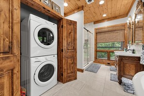 Bathroom featuring stacked laundry machines, wood-plank ceilings, and a walk-in shower. - Mountain-View Home w/ 3 Fireplaces | Sleeps 8 (Maggie Valley)