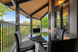 A covered outdoor patio with a round table and four chairs, overlooking a scenic landscape. - Mountain-View Home w/ 3 Fireplaces | Sleeps 8 (Maggie Valley)