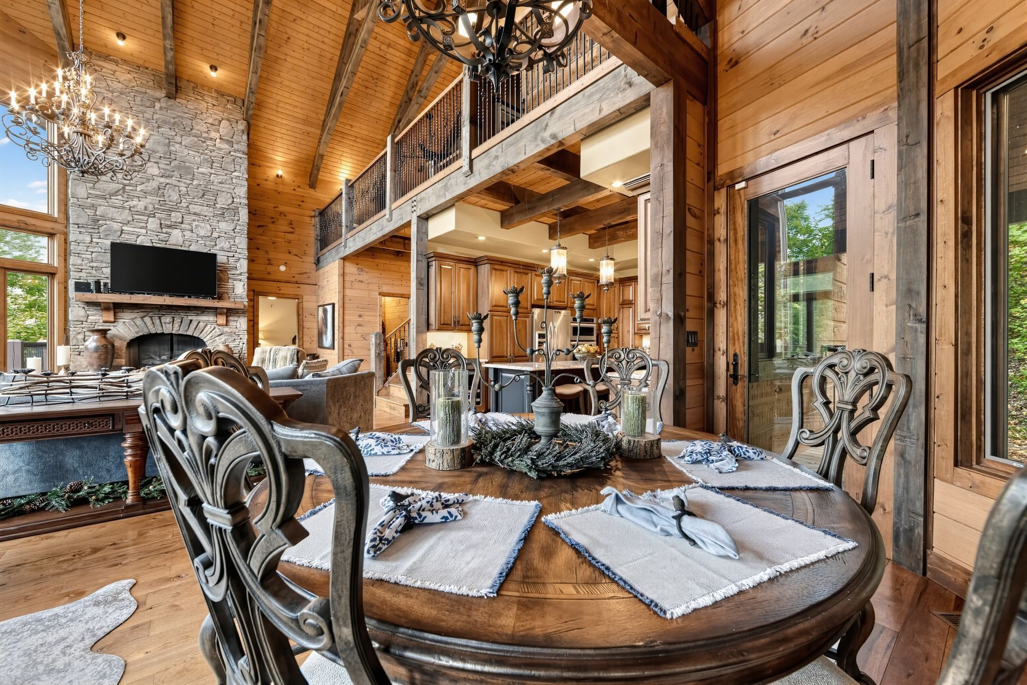 Une salle à manger spacieuse avec une table en bois dressée pour quatre personnes, entourée de chaises décorées.