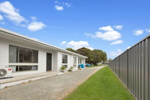 A row of modern, single-story buildings with large windows and a gravel driveway. - Lake & Tide: A fresh, modern escape close to Cunninghame Arm (Lakes Entrance)