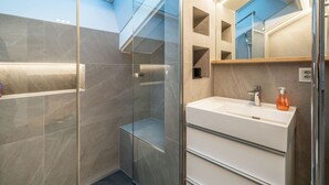 A modern bathroom with a glass shower enclosure, a white sink with a mirror above it, and a skylight above the shower. - Sky Penthouse with matterhorn view (Zermatt)