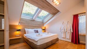 A bedroom with a skylight, a bed with white linens, two bedside tables with lamps, and a red curtain. - Sky Penthouse with matterhorn view (Zermatt)